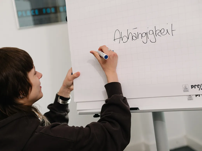 Eine junge Teilnehmerin schreibt das Wort "Abhängigkeit" auf ein Flip Chart | © ©LWLKS/JAlthoff 